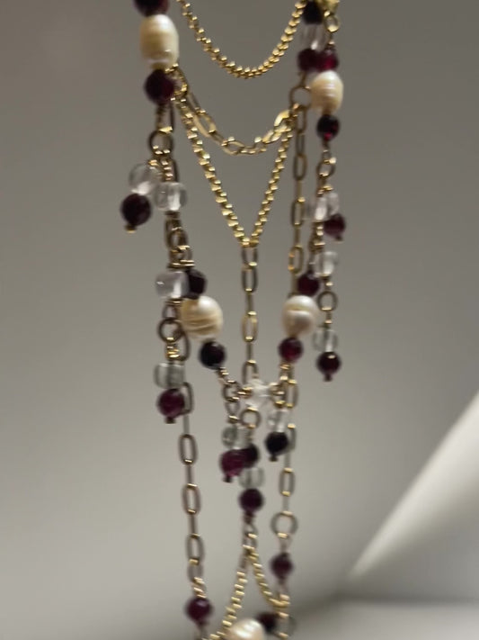 Collar largo de cadenas con granates y cristal de roca bañado en oro con pulsera compañera, video en movimiento, zoom.